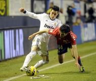 Real Madrid's Jose Maria Callejon (L) fights for the ball with Osasuna's Alejandro Arribas in Pamplona, January 12, 2013